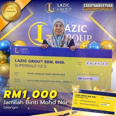 Lazic Group award recipient Dinara holding a large cheque for RM1,000, celebrating success in Malaysia.