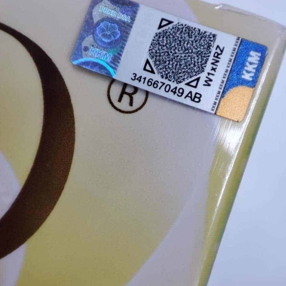 Barcode sticker on product packaging, close-up shot of holographic security label, with blurred background.